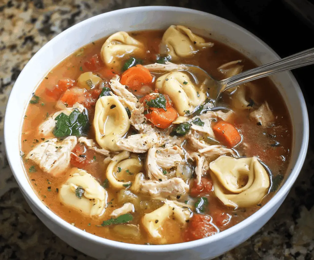 Creamy crockpot chicken tortellini soup in a bowl with chicken, cheese tortellini, spinach, and vegetables, perfect for a comforting meal