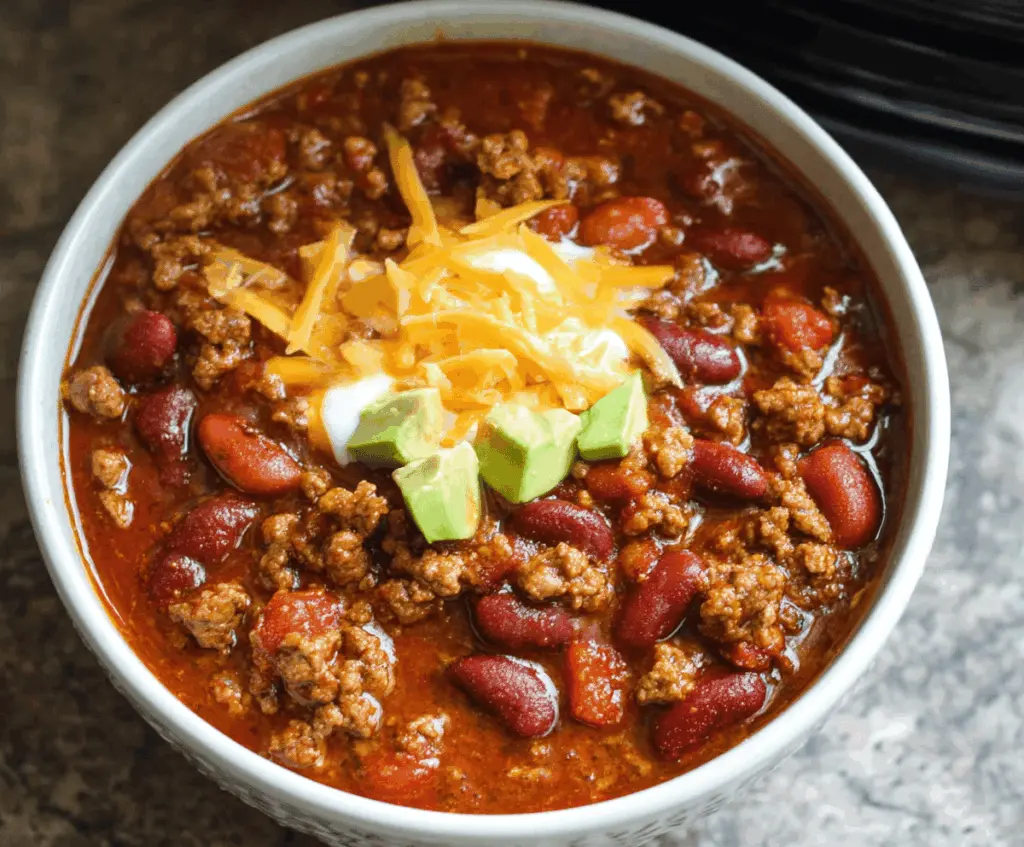 Delicious crockpot chili with ground beef, beans, tomatoes, and spices served in a bowl, perfect for cozy meals