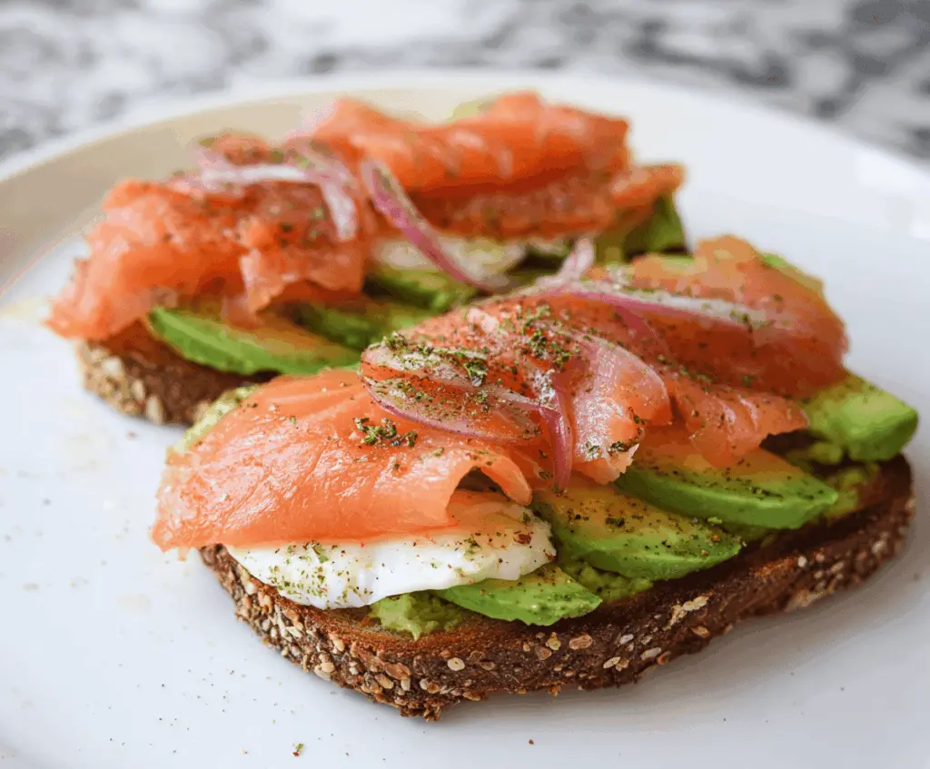 Delicious salmon and avocado toast topped with fresh herbs on a rustic wooden plate, perfect for a healthy breakfast or brunch.