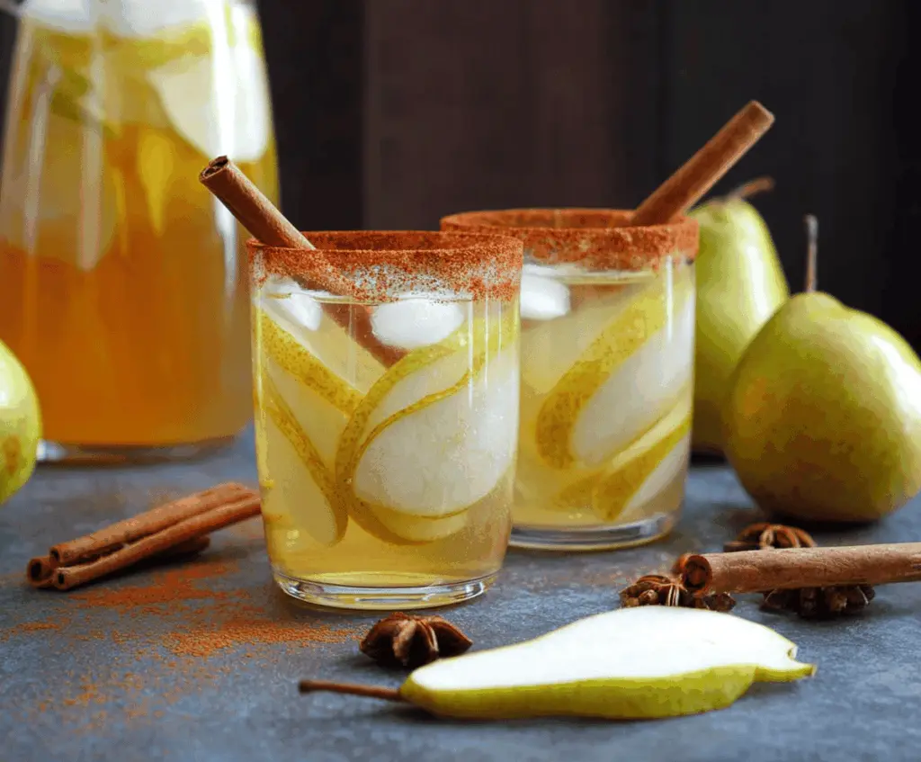 Refreshing spiced pear sangria with cinnamon sticks and honey, garnished with fresh pear slices and citrus, served in a glass pitcher for a flavorful autumn drink.