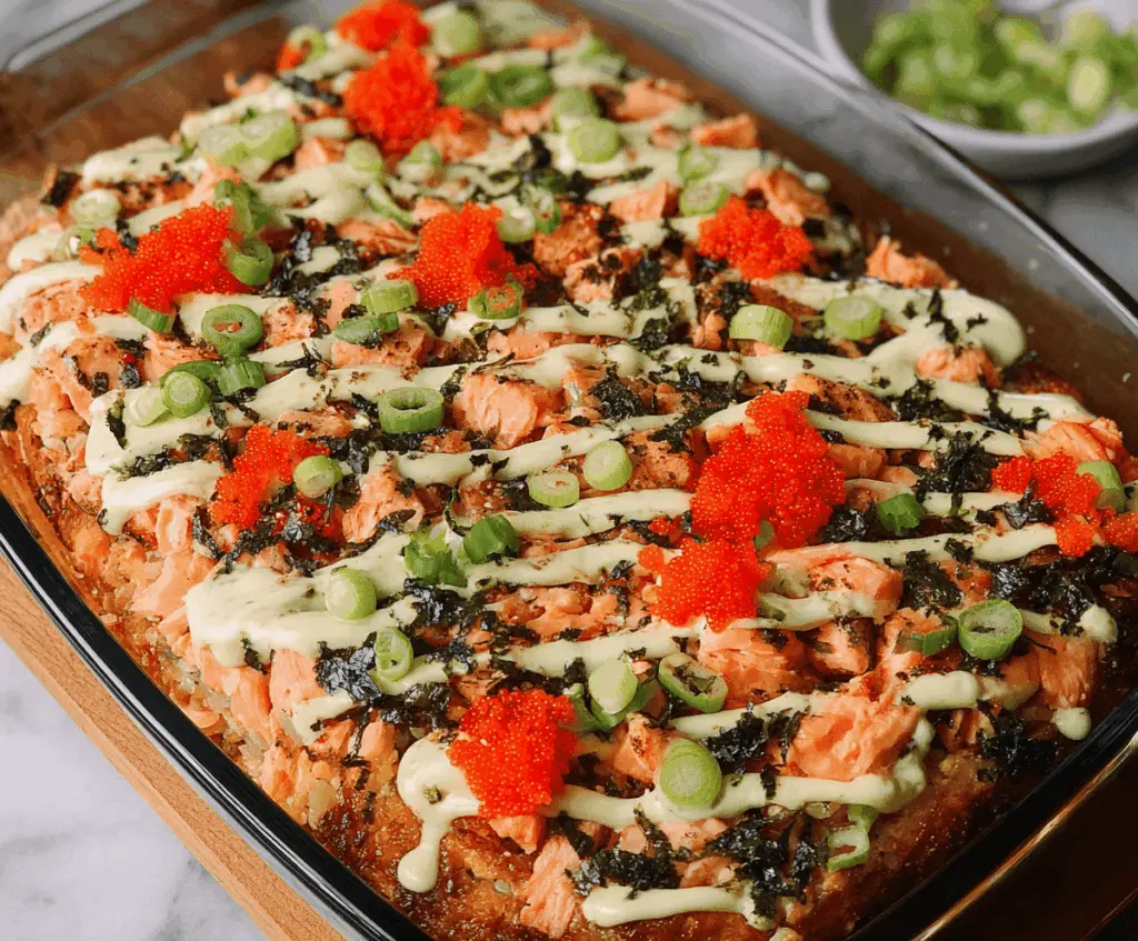 Creamy salmon sushi bake garnished with fresh herbs served in a baking dish.