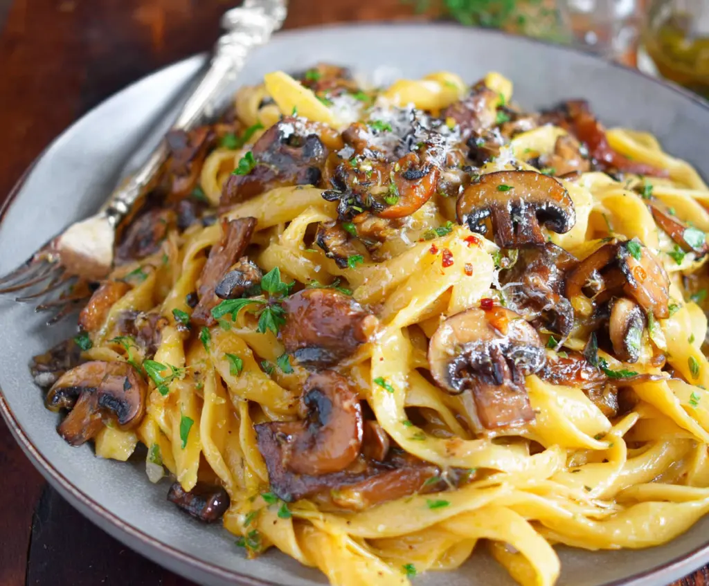Delicious mushroom pasta with creamy sauce served on a white plate.